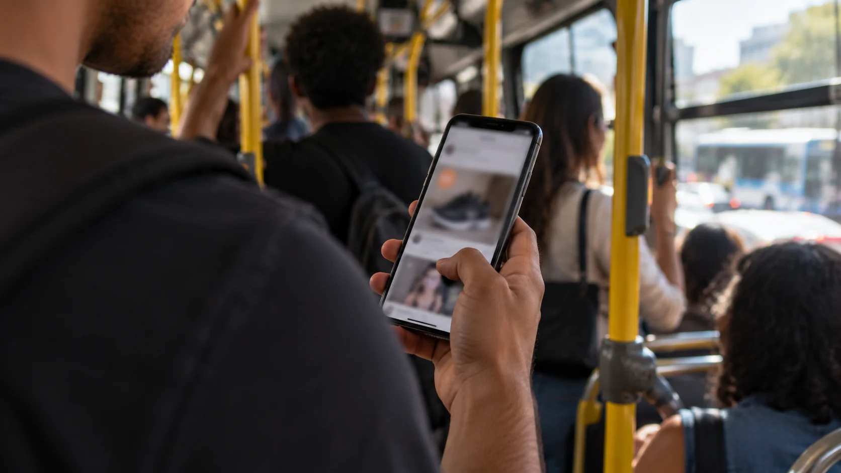 Passageiro rola o feed de uma rede social no celular dentro de um ônibus.